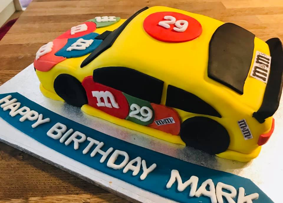 A cake in the shape of a NASCAR with MnM's logo's on Birthday & Novelty Cakes