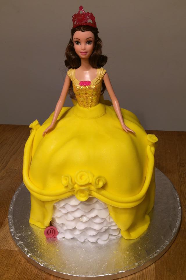A cake shaped into a princess barbie covered in yellow fondant 