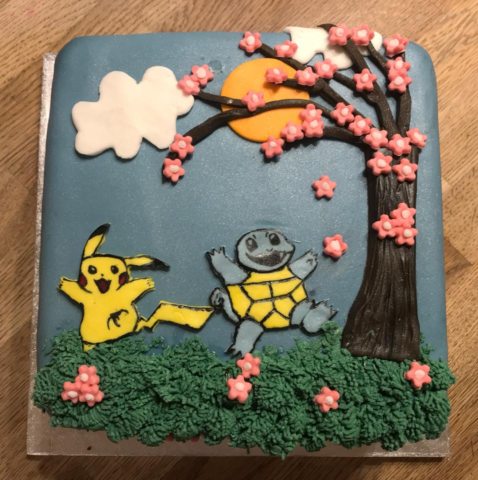 Square cake covered in fondant with pokemon figures in top under a fondant tree 