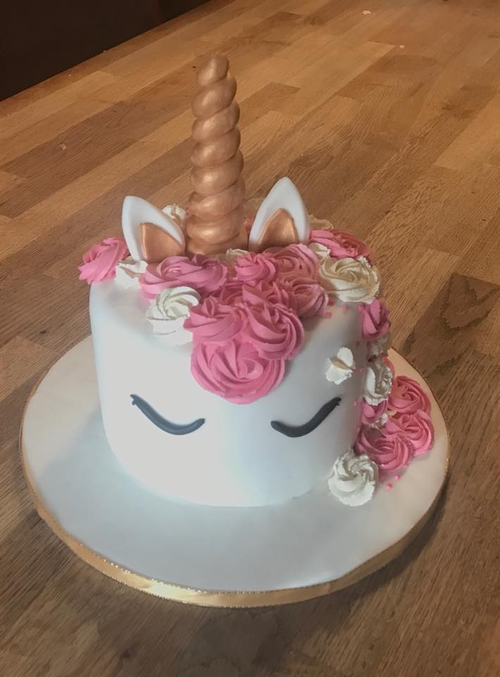 round cake covered in white fondant with a unicorn theme 