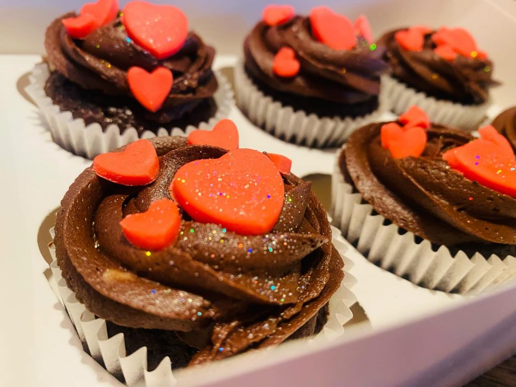 cupcakes with chocolate buttercream and red hearts on top 