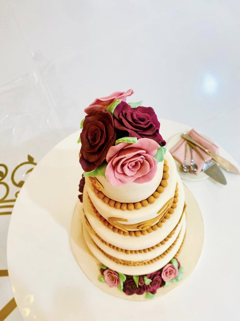 picture of a wedding cake with fondant roses on top and cutlery next toit 