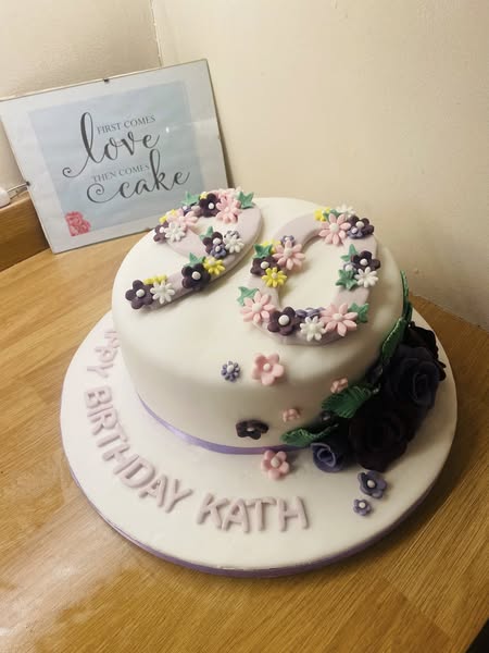 round cake covered in fondant with  number 90 on top with fondant flower 