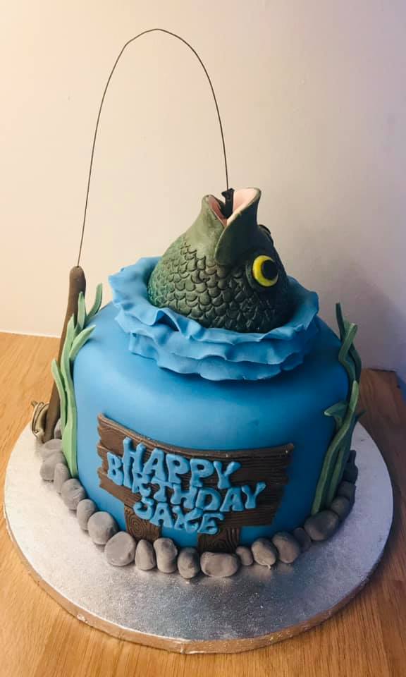 Round cake covered in blue fondant with  a  fondant fishes head and fishing line 