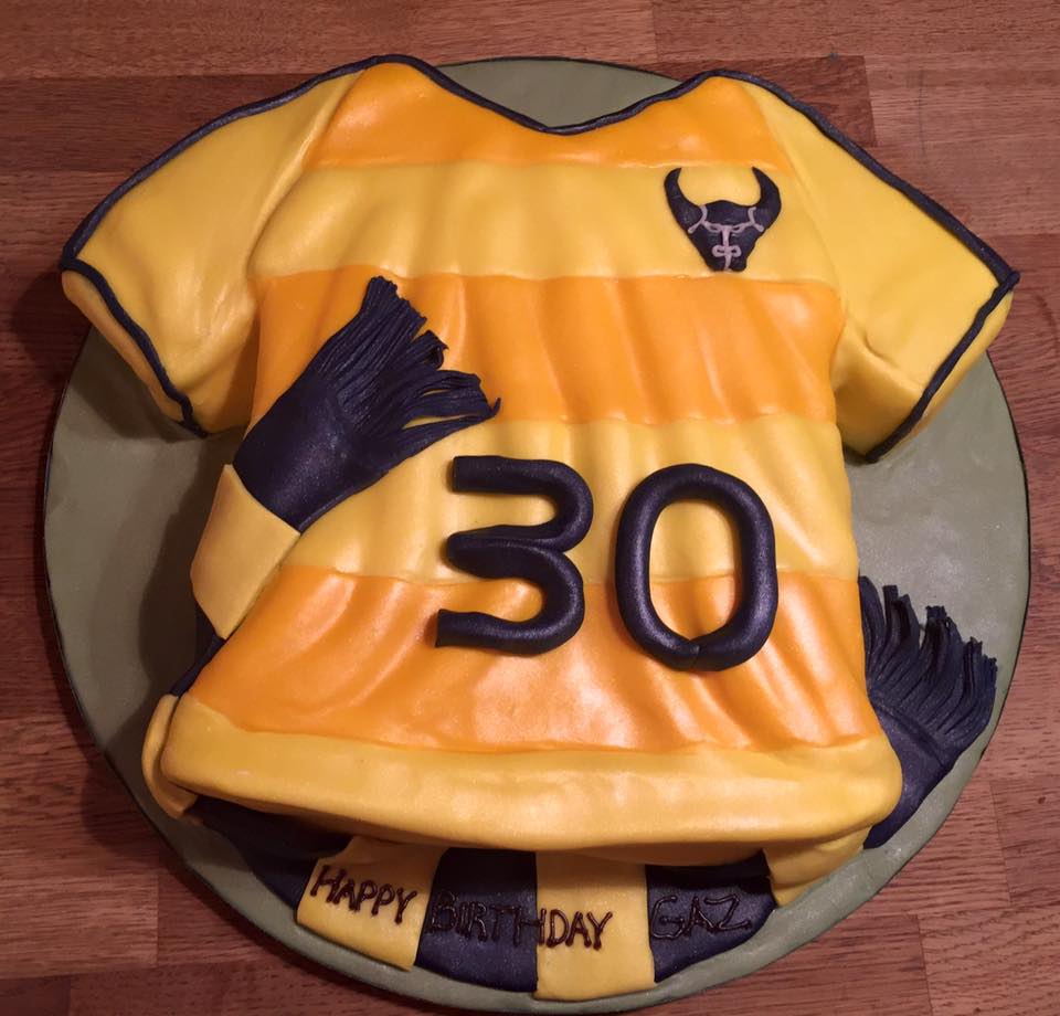 A cake in the shape of an Oxford United tshirt with the log and number 30 on it 