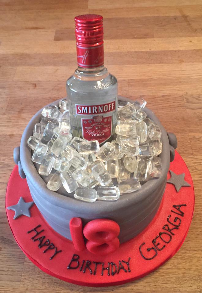 Round cake covered in fondant to look like an ice bucket with fake ice cubes and a vodka bottle on top 