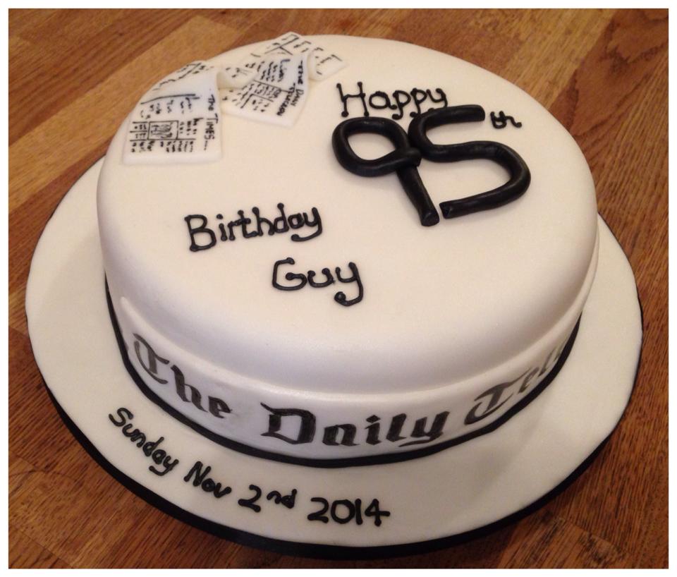 Round cake covered in white fondant with a fondant newspaper and number 95 on top